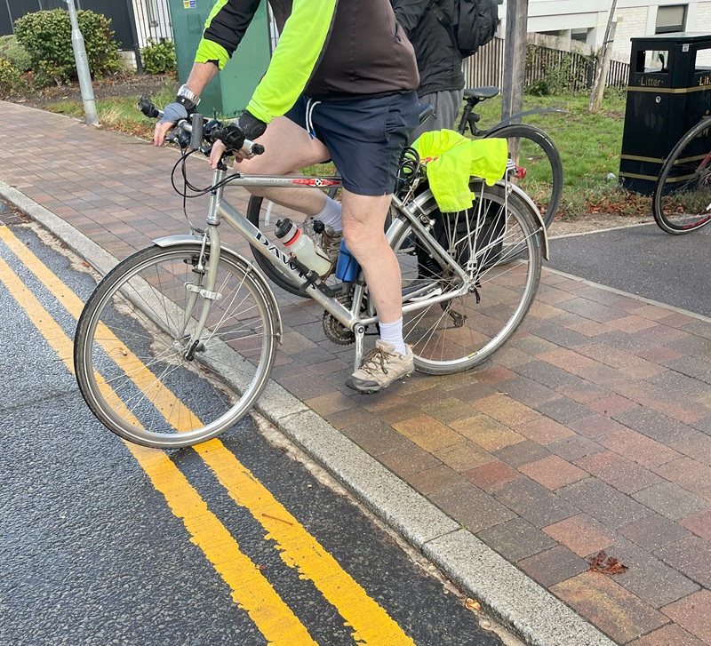 A cyclist leaves a pavement crossing to enter the road with the front wheel dropping down over a kerb.